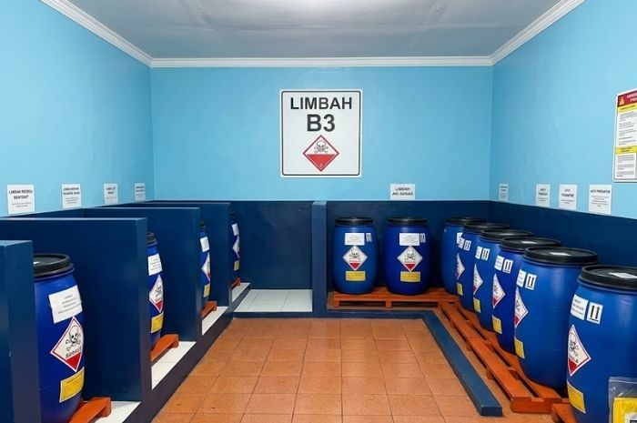 Fasilitas penyimpanan limbah B3 dengan kemasan tertutup, area penampung tumpahan, dan tata letak yang teratur.